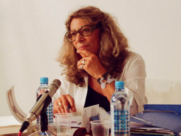 Photographie de Barbara Cassin lors d'un conférence, assise à un table, un micro disposé devant elle