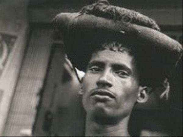 Photographie en noir et blanc d'un homme noir portant du linge plié sur la tête
